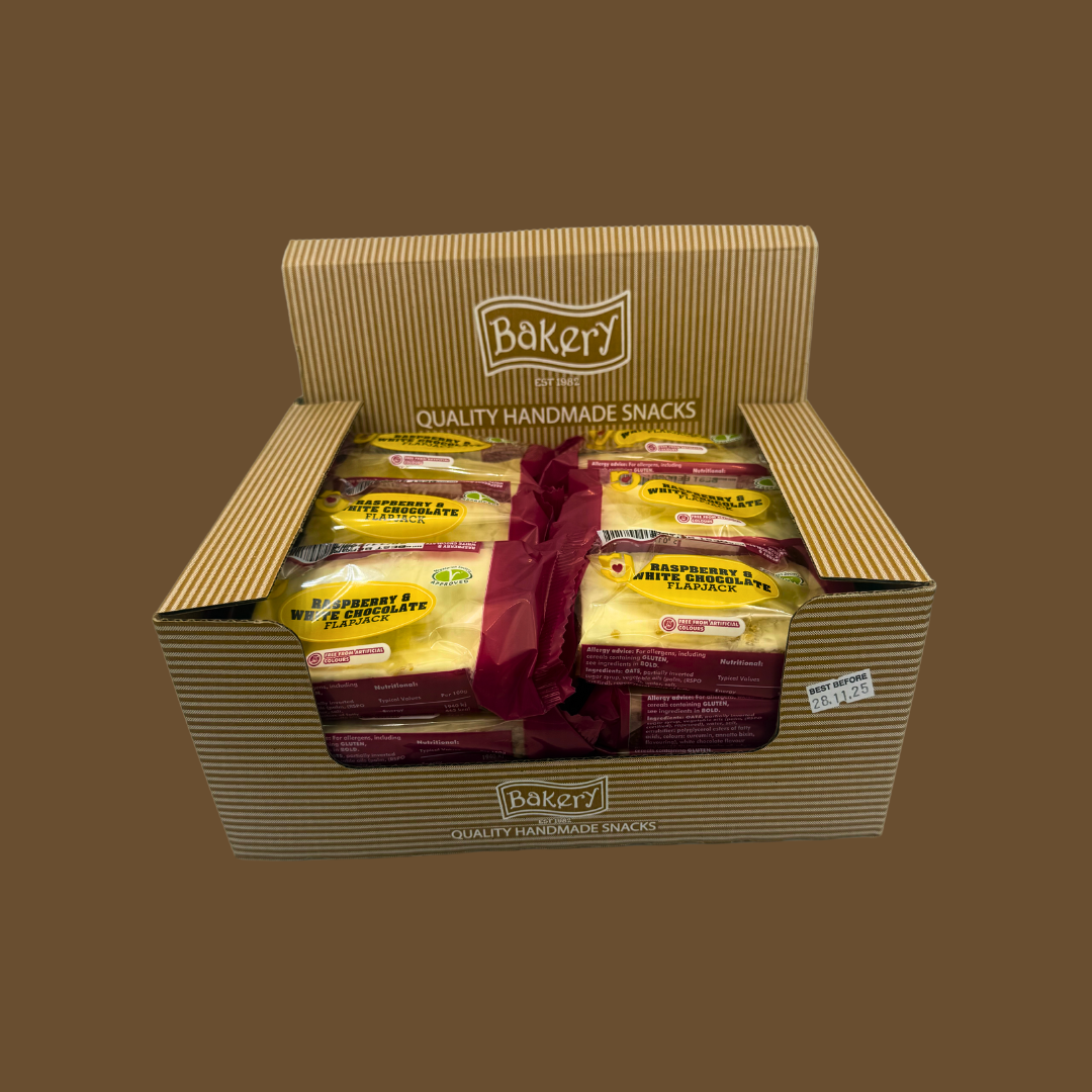 Open cereal snack bar beside fresh raspberries and a white chocolate block