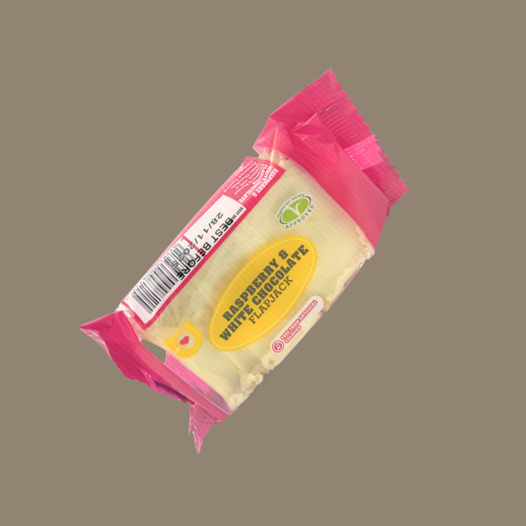 Hand holding a raspberry & white chocolate flapjack over a gym towel