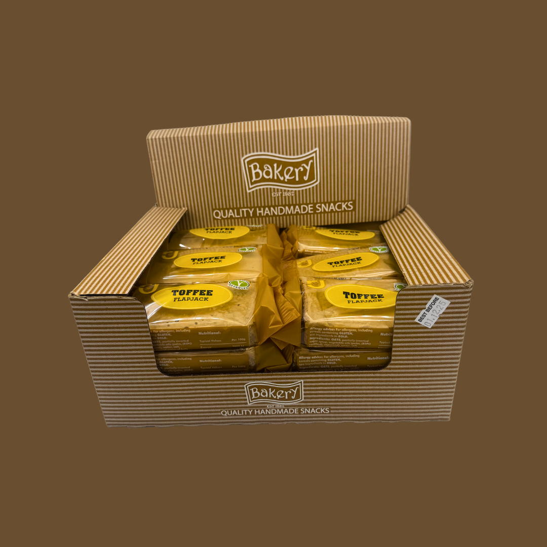 Open cereal snack bar beside a mug of coffee and a toffee piece