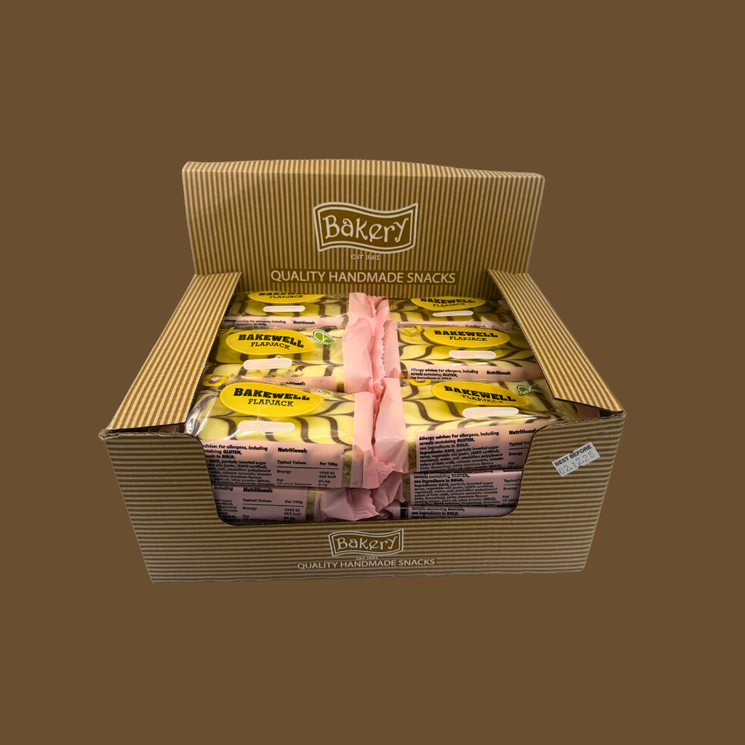 Opened flapjack beside a mug of tea and cherry bakewell tart