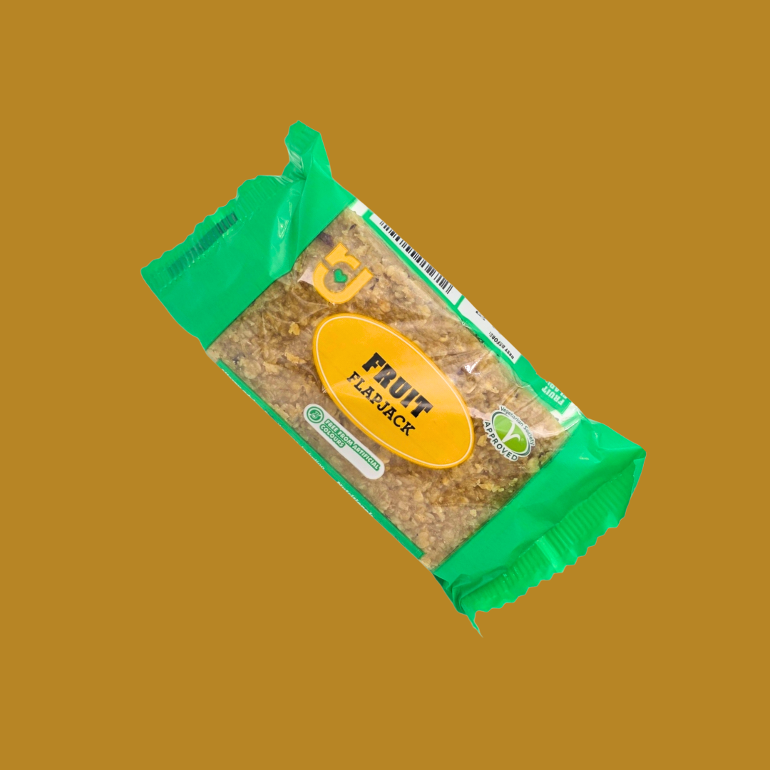 Hand holding a granola flapjack bar over a picnic blanket with fruit