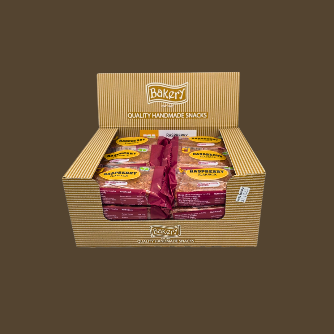 Raspberry flapjack bar beside fresh raspberries and a glass of juice