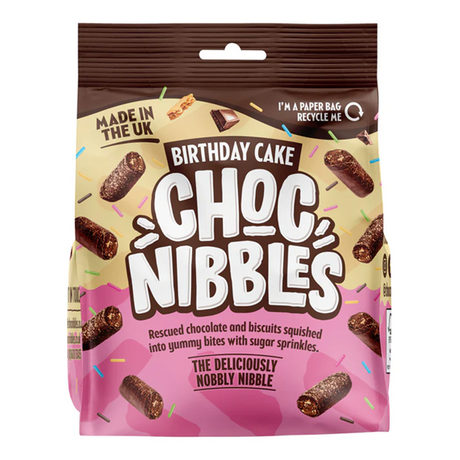 Close-up of a Chocolate Nibbles Birthday Cake (135g) from a 12‑pack — moist chocolate sponge with glossy chocolate icing and multicolored sprinkles, retail packaging visible