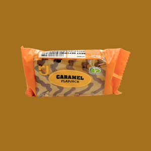 Hand holding a caramel snack bar against a picnic blanket backdrop