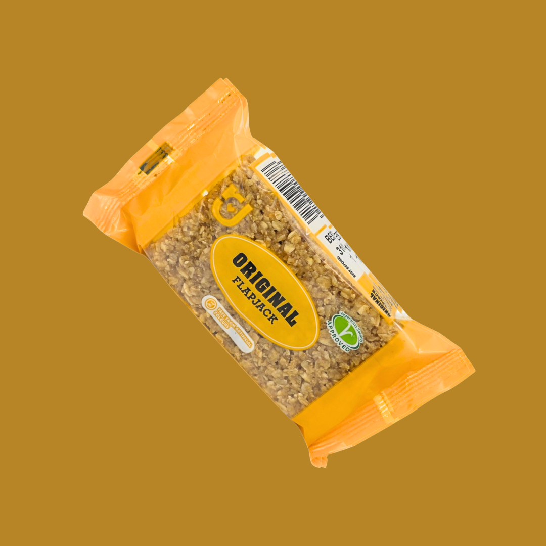 Hand holding one flapjack bar with mixed-flavor pack in the background
